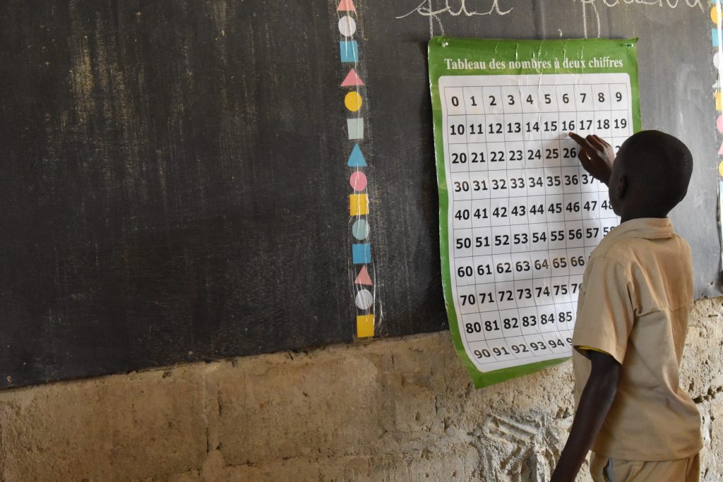 A child in a TaRL classroom in Côte d'Ivoire reads a number chart on the board.